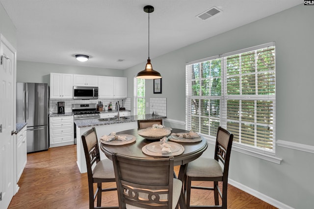 dining space with baseboards, visible vents, and light wood-type flooring