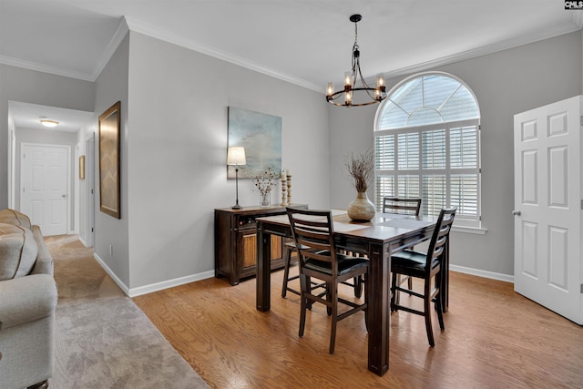 dining room with baseboards, ornamental molding, light wood-type flooring, and a chandelier
