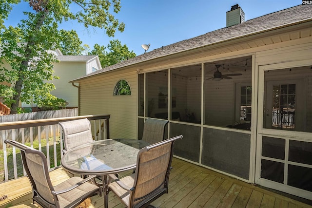 wooden terrace with fence, a ceiling fan, outdoor dining space, and a sunroom