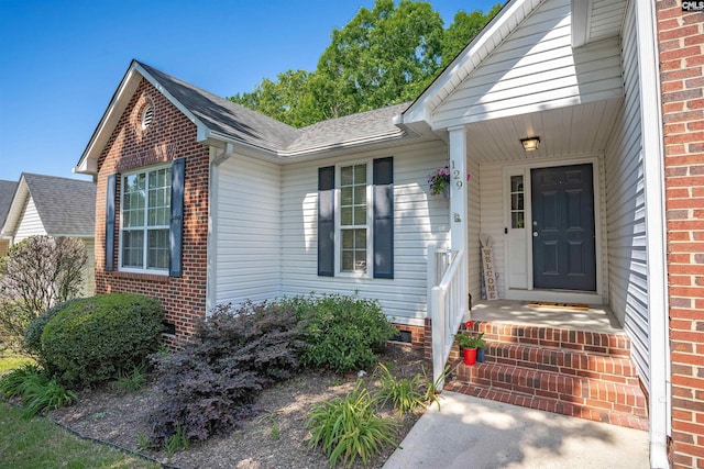 property entrance with brick siding and a shingled roof