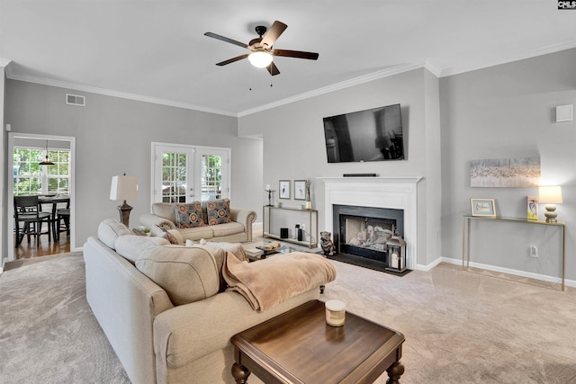 carpeted living room with crown molding, baseboards, ceiling fan, and visible vents