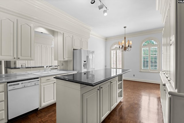kitchen with hanging light fixtures, a sink, white cabinets, an inviting chandelier, and white appliances