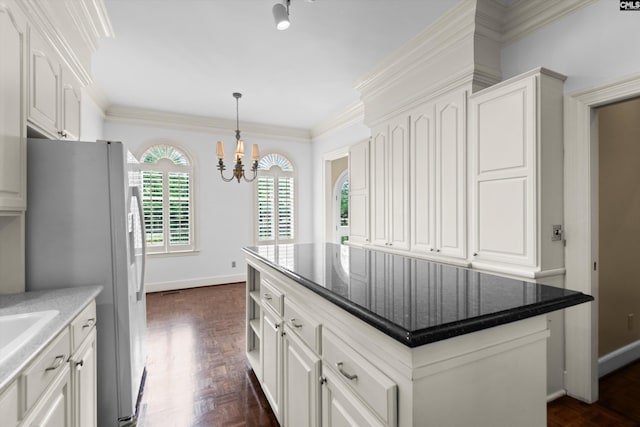 kitchen featuring freestanding refrigerator, white cabinetry, a notable chandelier, and a center island