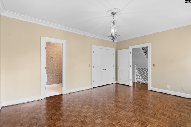 spare room featuring baseboards, crown molding, and a chandelier