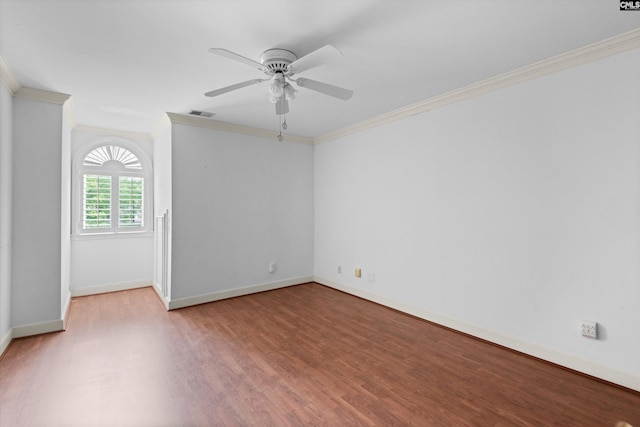 empty room with visible vents, ornamental molding, wood finished floors, baseboards, and ceiling fan