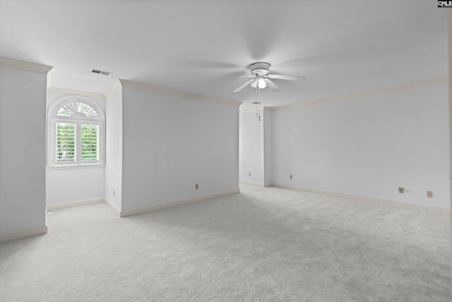 unfurnished room with a ceiling fan, visible vents, crown molding, baseboards, and light carpet