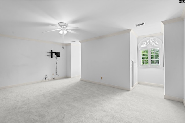 empty room with crown molding, light carpet, a ceiling fan, and visible vents
