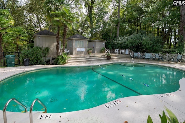 pool featuring a patio area, fence, and an outbuilding