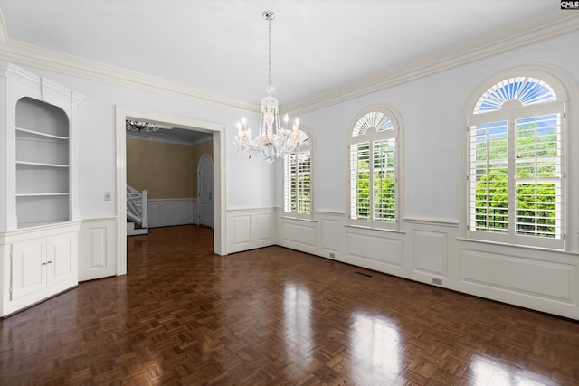 unfurnished dining area featuring an inviting chandelier, ornamental molding, a decorative wall, stairway, and a wainscoted wall