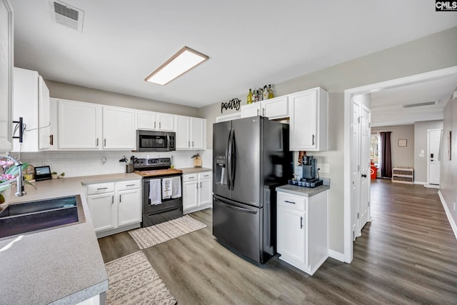 kitchen with visible vents, wood finished floors, a sink, black appliances, and white cabinetry