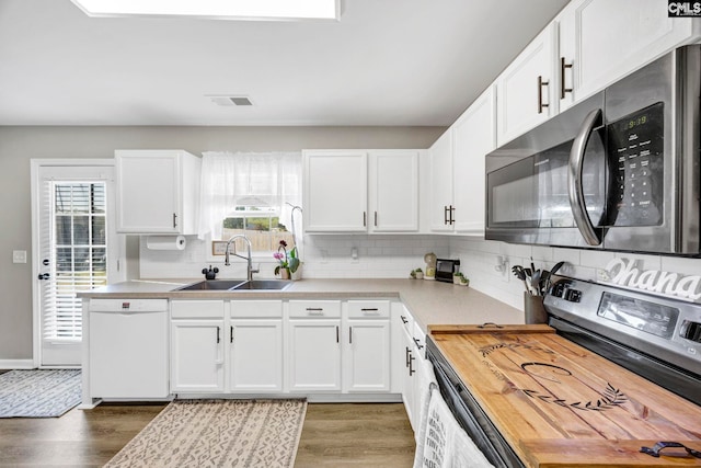 kitchen with a sink, plenty of natural light, stainless steel appliances, wood finished floors, and visible vents