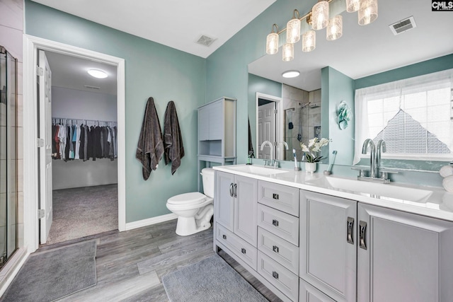 full bath with a sink, a shower stall, wood finished floors, and visible vents