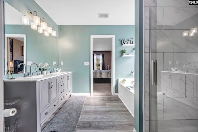 full bathroom with visible vents, double vanity, connected bathroom, and wood finished floors