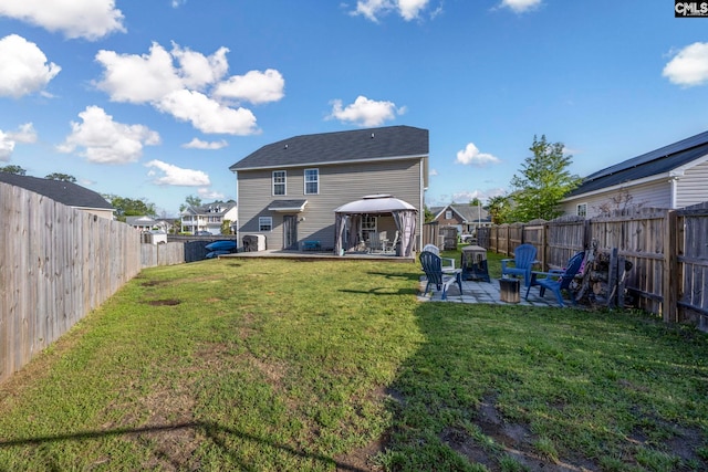 rear view of property with a fenced backyard, a gazebo, a yard, and a patio area