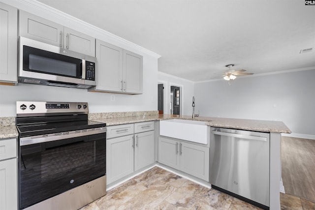 kitchen featuring a sink, stainless steel appliances, a ceiling fan, a peninsula, and ornamental molding