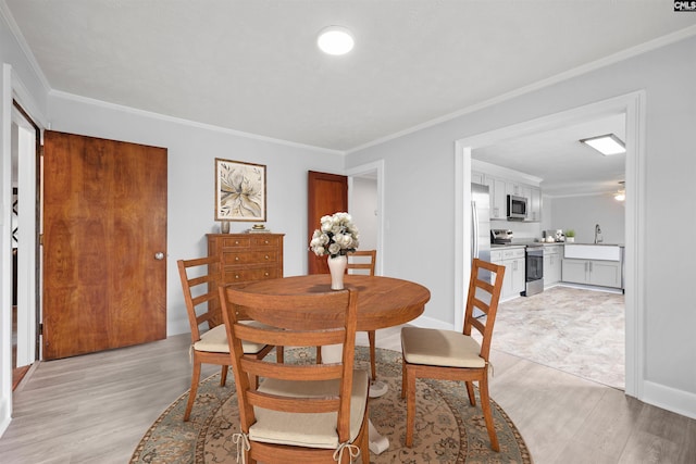 dining room with ornamental molding and light wood-style floors