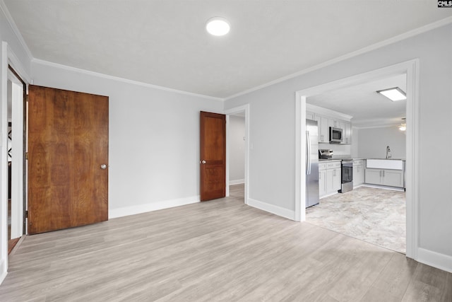 unfurnished living room with ornamental molding, a sink, and light wood-type flooring