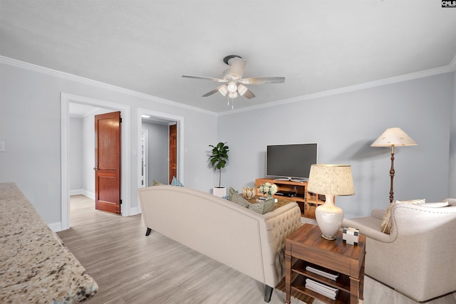 living area with light wood-style floors, a ceiling fan, baseboards, and ornamental molding