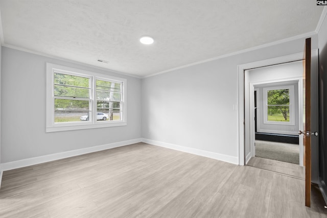 empty room featuring crown molding, light wood-style flooring, and a healthy amount of sunlight