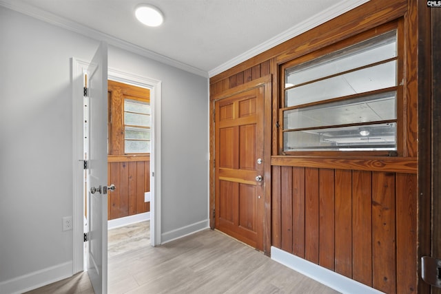 entrance foyer with crown molding, baseboards, wood walls, and wood finished floors