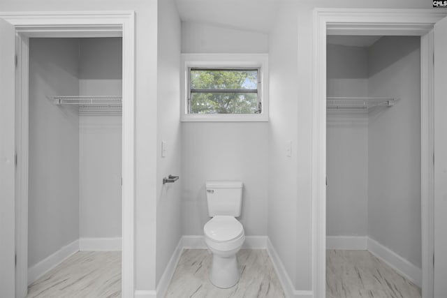 bathroom featuring baseboards, a spacious closet, and toilet