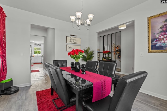 dining area with baseboards, wood finished floors, and a notable chandelier