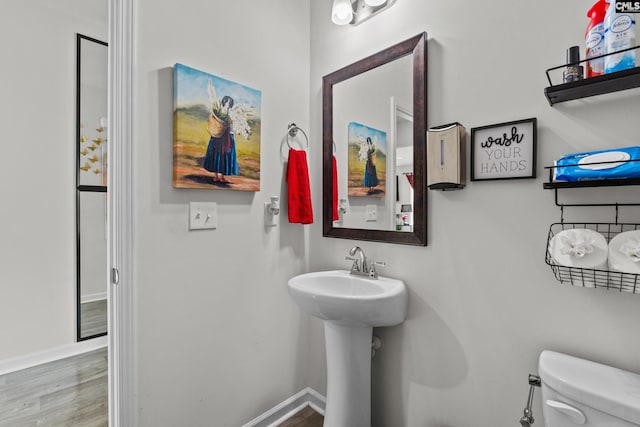bathroom with baseboards, toilet, and wood finished floors
