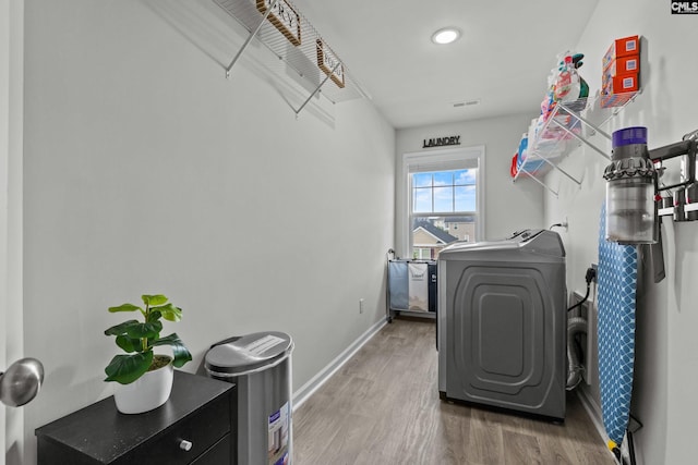 clothes washing area with laundry area, visible vents, wood finished floors, baseboards, and washer / clothes dryer
