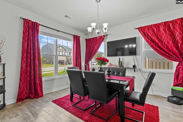 dining room with baseboards, an inviting chandelier, wood finished floors, and visible vents