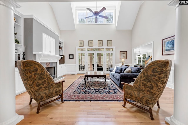 living area featuring light wood finished floors, ceiling fan, a high ceiling, and a healthy amount of sunlight
