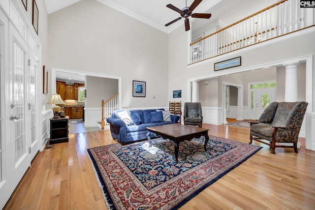 living room featuring a healthy amount of sunlight, ceiling fan, light wood-style floors, and a towering ceiling