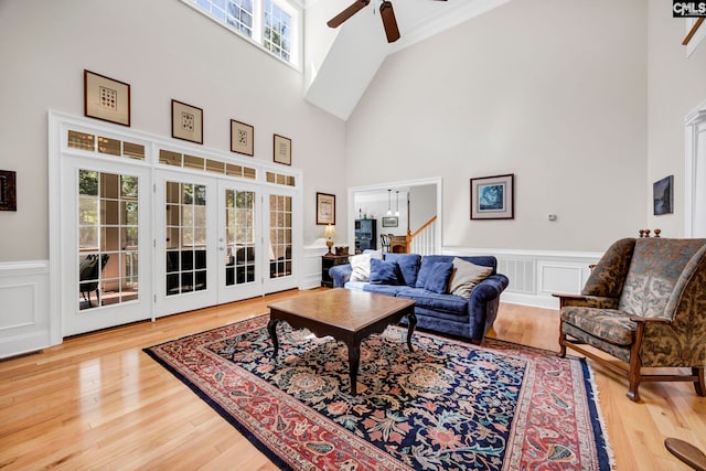 living area featuring wainscoting, high vaulted ceiling, a ceiling fan, and wood finished floors