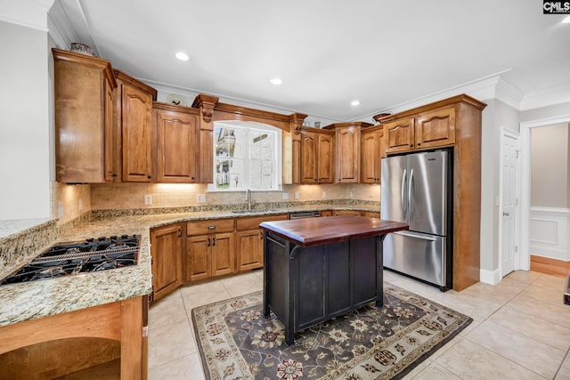 kitchen with brown cabinets, stainless steel appliances, ornamental molding, and decorative backsplash