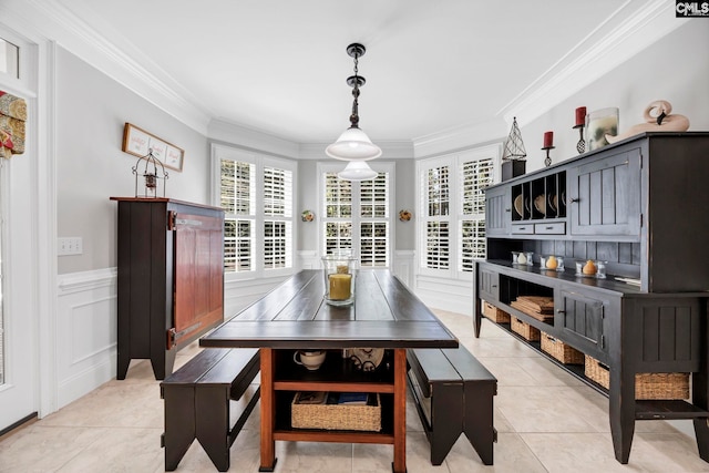 dining area with crown molding, a wainscoted wall, and a decorative wall