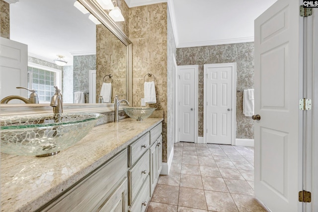 full bath featuring double vanity, a sink, baseboards, ornamental molding, and wallpapered walls