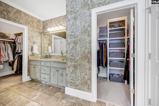 full bathroom with vanity, ornamental molding, baseboards, a walk in closet, and wallpapered walls