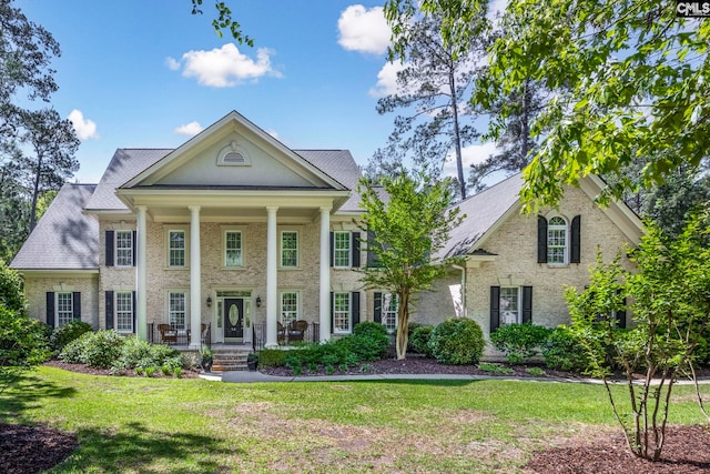 greek revival inspired property with covered porch and a front lawn