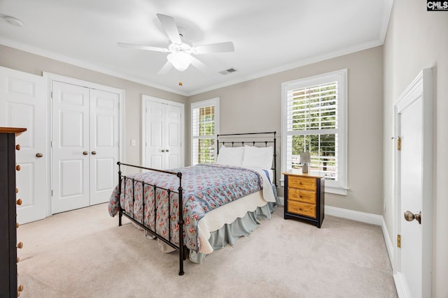 bedroom featuring carpet flooring, crown molding, visible vents, and two closets