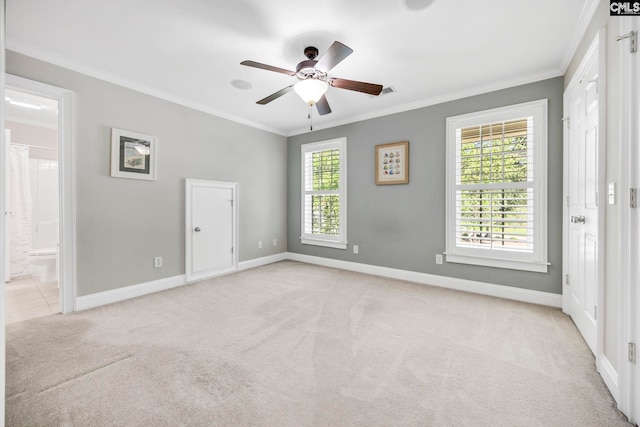 empty room with baseboards, ornamental molding, ceiling fan, and light colored carpet