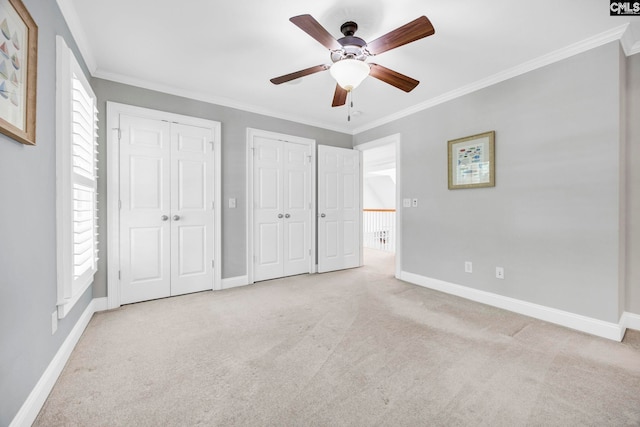 unfurnished bedroom featuring crown molding, baseboards, multiple closets, and carpet