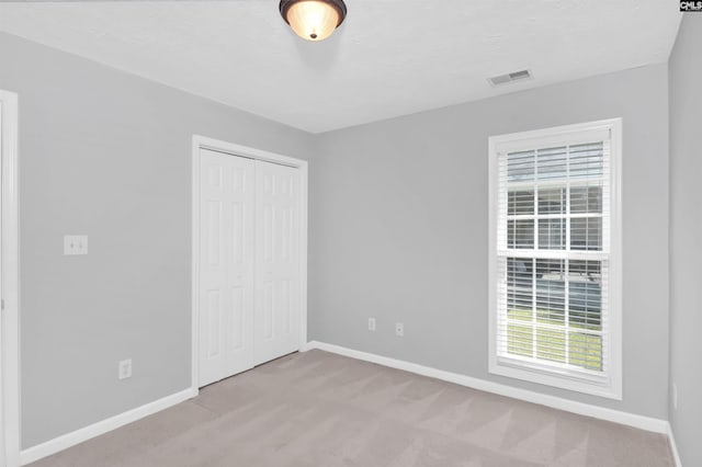 unfurnished bedroom featuring visible vents, carpet flooring, baseboards, and a closet