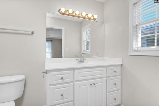 bathroom with toilet, baseboards, a healthy amount of sunlight, and vanity