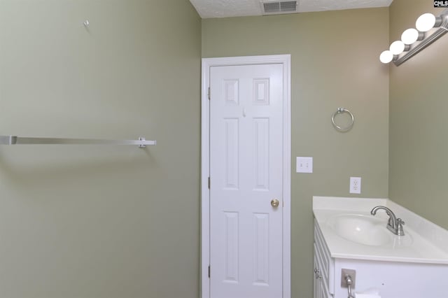 bathroom with vanity, a textured ceiling, and visible vents