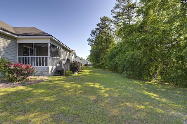 view of yard featuring a ceiling fan and a sunroom