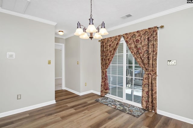 unfurnished dining area featuring visible vents, ornamental molding, wood finished floors, baseboards, and a chandelier