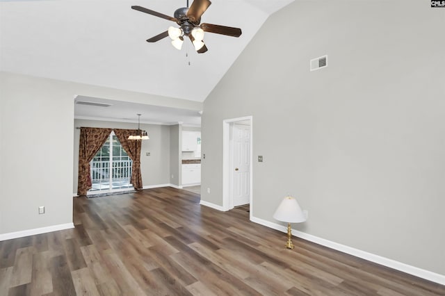 unfurnished living room with ceiling fan with notable chandelier, wood finished floors, and high vaulted ceiling