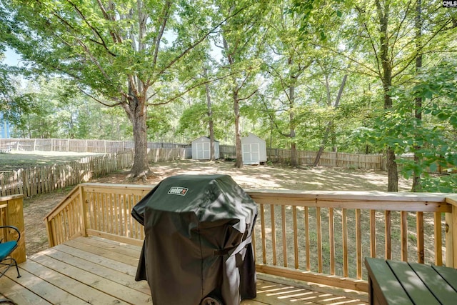 wooden deck with an outdoor structure, a shed, a fenced backyard, and a grill