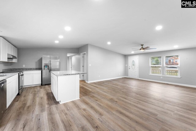 kitchen with wall chimney range hood, a center island, recessed lighting, a ceiling fan, and stainless steel appliances