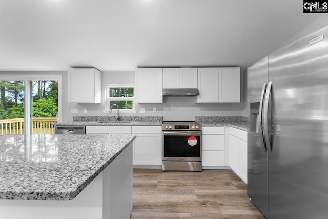 kitchen with white cabinets, stainless steel appliances, a sink, and light wood-type flooring