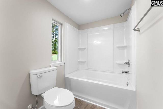 bathroom featuring washtub / shower combination, toilet, and wood finished floors